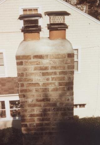 After: the rebuilt red-brick chimney with a new cap on the house