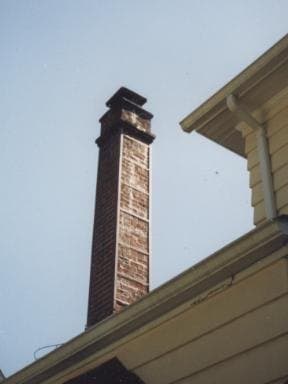 Tall brick chimney reinforced with steel braces at the roofline