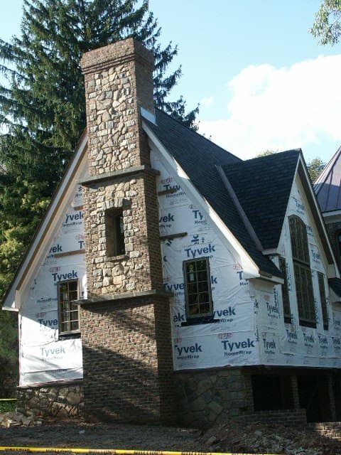 Stone-veneer chimney with a carved stone window niche on a home under construction