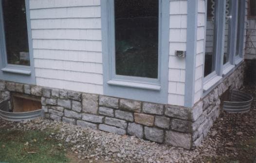 Stone veneer foundation along the base of a home beneath the siding
